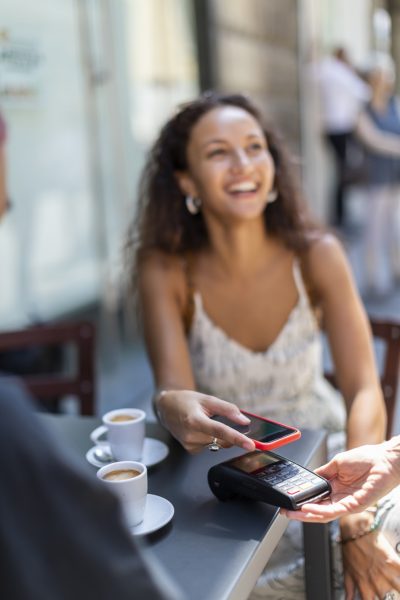 Young Woman Paying With Mobile Contactless App at Cafe